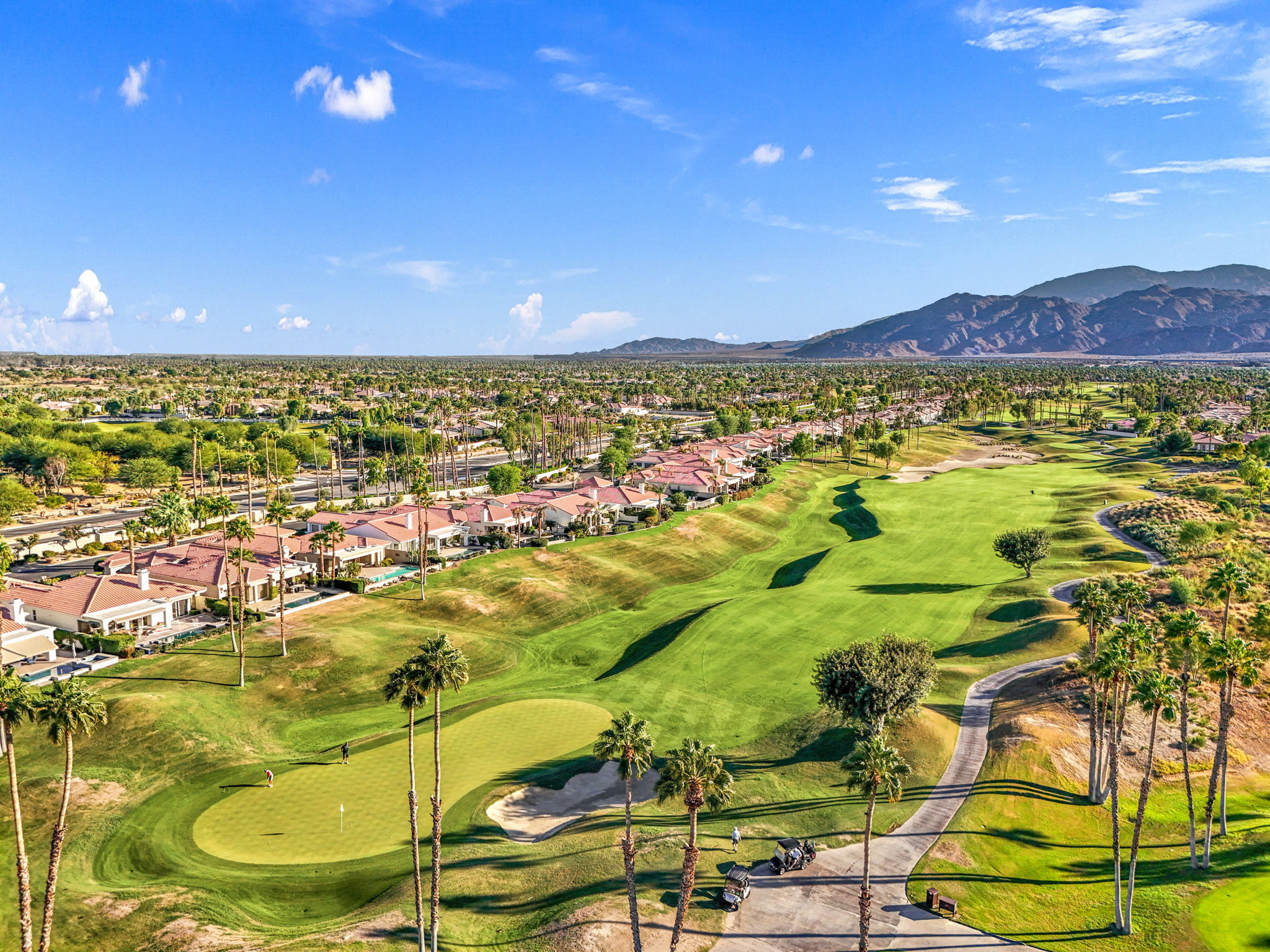 Aerial view of PGA West in La Quinta — fairways, mountain backdrop, and resort pools under clear desert skies