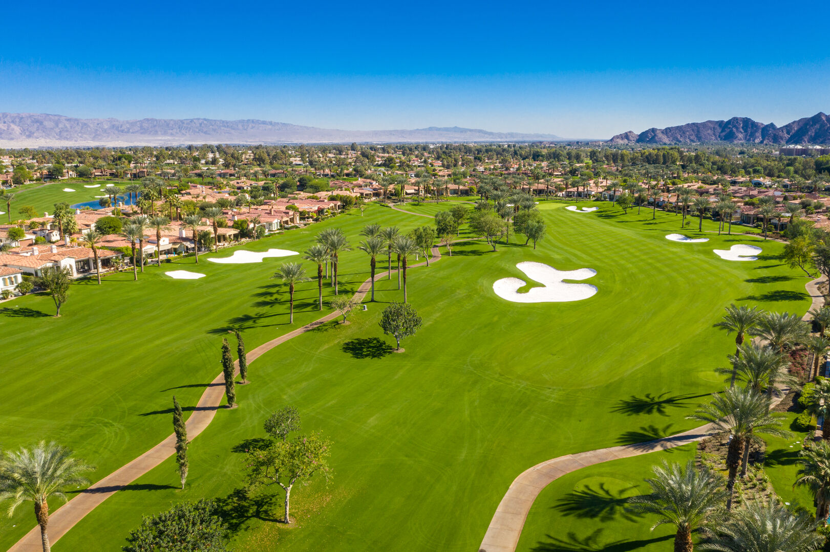 Aerial view of Indian Wells in the California Desert — palm-lined streets, mountain backdrop, and resort pools